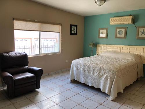 a bedroom with a bed and a chair and a window at Almejas B in San Carlos
