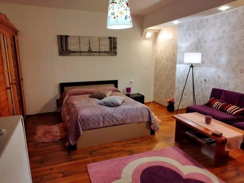 sypialnia z łóżkiem i fioletową kanapą w obiekcie Milu Residence 2 w mieście Ghimbav