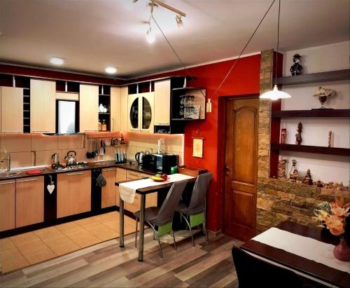 una cucina con pareti rosse, tavolo e sedie di Milu Residence 2 a Ghimbav