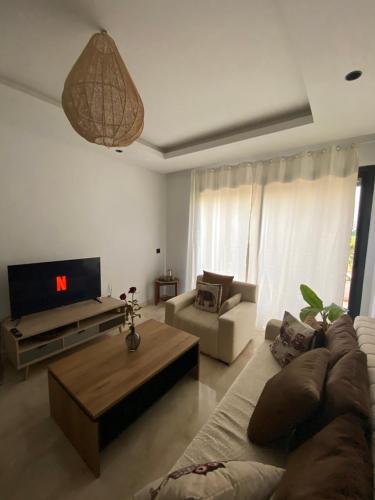 uma sala de estar com um sofá e uma televisão em Duplex luxe - Résidence privée - Casablanca/Bouskoura em Bouskoura