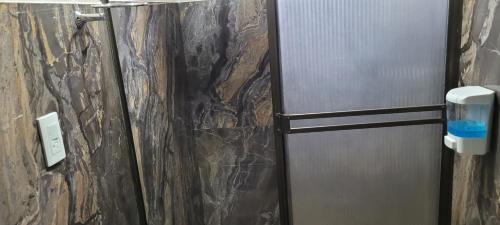 baño con nevera de acero inoxidable junto a una pared de piedra en Apartamento confort centro, en Pasto