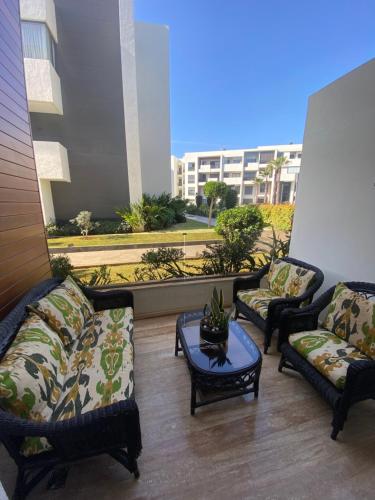 uma sala de estar com sofás, uma mesa e uma varanda em Duplex luxe - Résidence privée - Casablanca/Bouskoura em Bouskoura