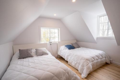 2 camas en una habitación con paredes y ventanas blancas en Bright Amazing 6 Bed Chalet Waterfront in Rigaud, en Rigaud