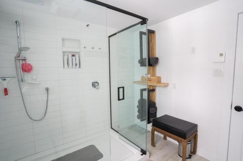a bathroom with a glass shower with a stool at Bright Amazing 6 Bed Chalet Waterfront in Rigaud in Rigaud