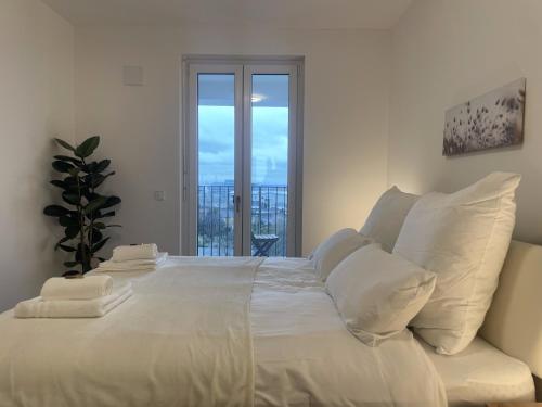 a large white bed with white pillows and a window at Luxurious and stylish apartment at BER Airport in Schönefeld