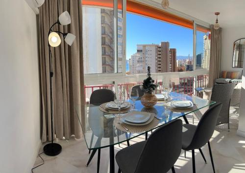 uma sala de jantar com uma mesa de vidro e cadeiras em Apartamento BENILOVE, en playa Benidorm em Benidorm
