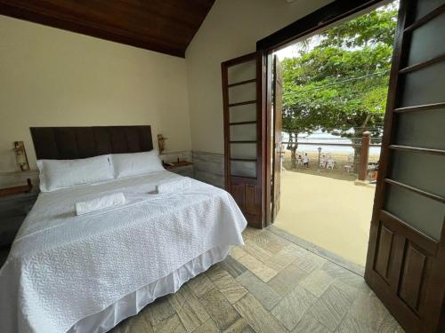 Schlafzimmer mit einem Bett und einer Glasschiebetür in der Unterkunft Encanto Paraty Beach in Paraty
