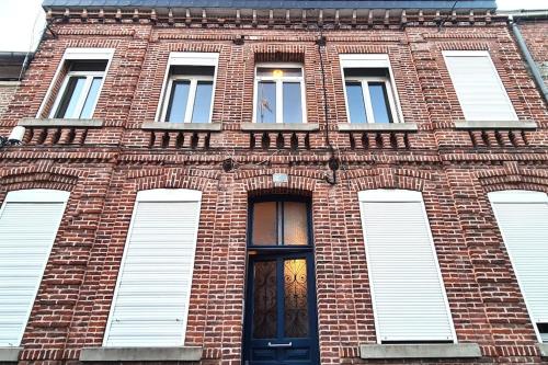 - un bâtiment en briques avec une porte et des fenêtres noires dans l'établissement Le cocon paisible 1er étage - Idéal travailleurs - Voyages, à Valenciennes