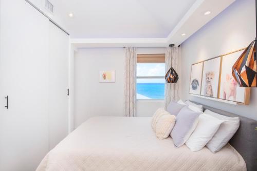 um quarto branco com uma cama com almofadas brancas em Grape Tree Condo #10 em George Town