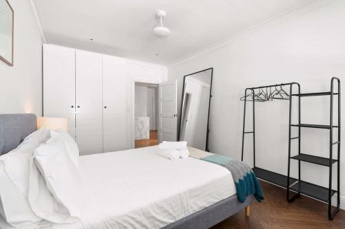 a white bedroom with a bed and a ladder at Sunlit and Spacious Apt in the Heart of the East in Sydney