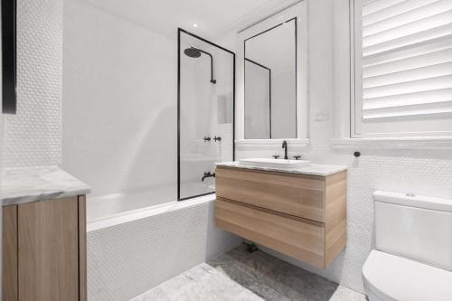 uma casa de banho com um lavatório, um espelho e uma banheira em Sunlit and Spacious Apt in the Heart of the East em Sidney