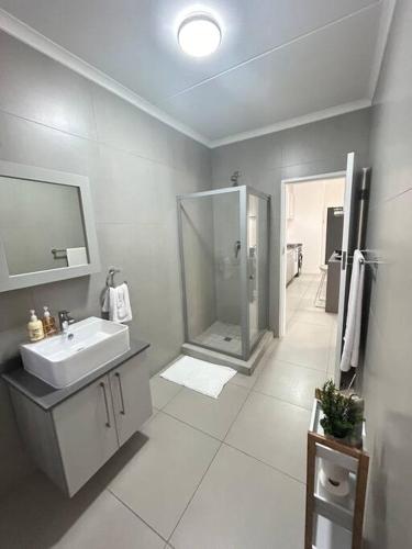een badkamer met een douche en een wastafel bij Cozy apartment in Carlswald in Midrand