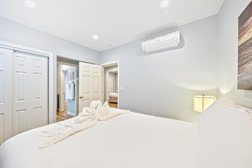 a white bedroom with a large white bed and a fan at Cozy 3 Bedroom Across from Playground on the Beach in Newport Beach