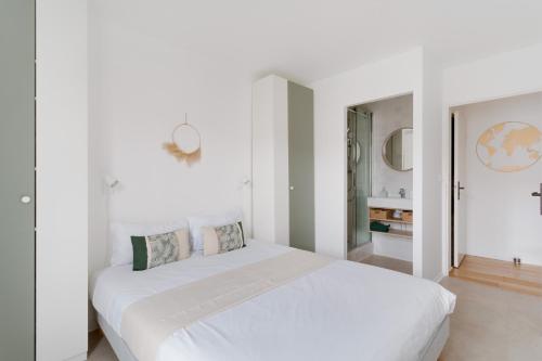 ein weißes Schlafzimmer mit einem weißen Bett und einem Badezimmer in der Unterkunft La Serrisienne 4 - Val d'Europe - Disneyland Paris - 6 à 8 Personnes in Serris