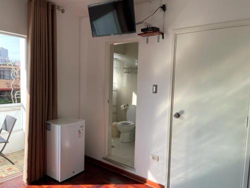 a bathroom with a toilet and a television on a wall at Lima HOUSE MILANI in Lima