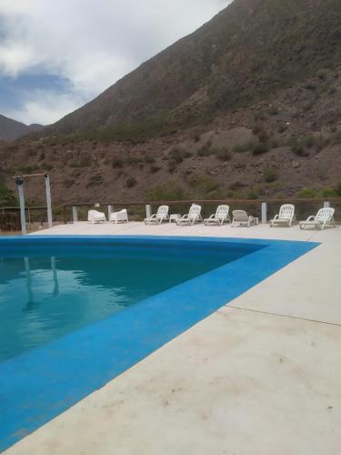 a swimming pool with chairs and mountains in the background at Cabaña Las Flores in Potrerillos
