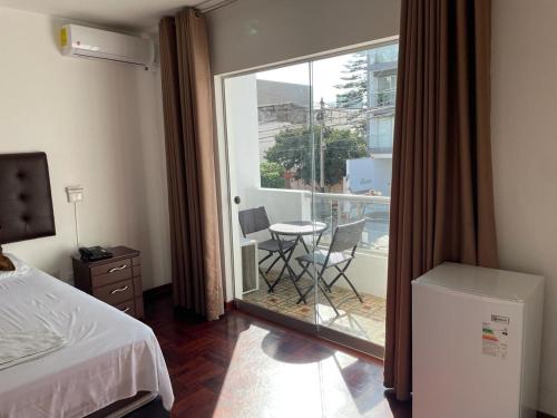 1 dormitorio con 1 cama y balcón con mesa y sillas en Lima HOUSE MILANI, en Lima