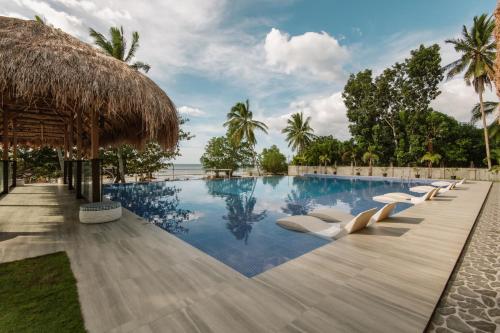 a pool at the resort with lounge chairs and a thatched roof at Kaway Resort & Spa in Tabuelan