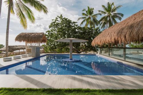 a swimming pool with an umbrella and palm trees at Kaway Resort & Spa in Tabuelan