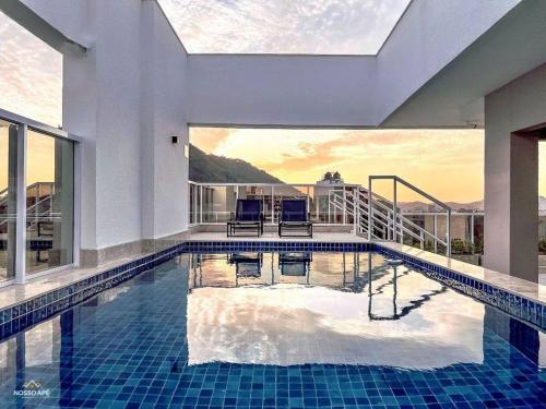a swimming pool with two chairs in a house at Nosso Apê 915: Piscina | TV Box | Academia - NA2002 in Juiz de Fora