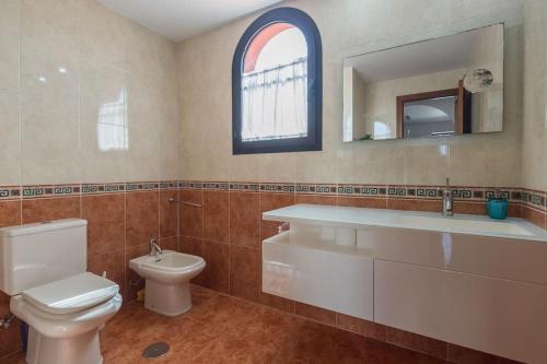 Un baño con inodoro, lavabo y espejo. en Ático con terraza en Agaete, en Agaete
