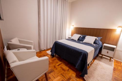 a bedroom with a bed and two chairs at Loft Coração da Serra in Serra Negra