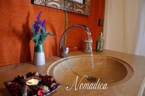 a sink with a candle and a vase of flowers at Nomadica Desert Camp in Merzouga