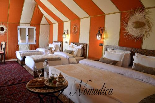 メルズーガにあるNomadica Desert Campのベッド4台とテーブル付きの部屋、