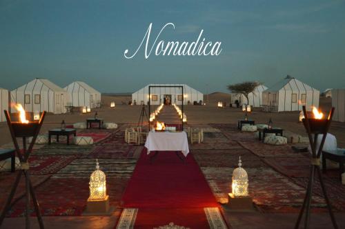 a marquee with a table and some white tents at Nomadica Luxury Camp in Merzouga