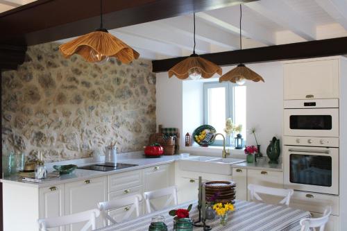 una cocina con armarios blancos y una mesa con sillas. en RUSTIC HOMES en San Vicente de la Barquera