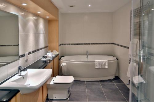a bathroom with a tub and a toilet and a sink at Best Western Plus Ullesthorpe Court Hotel & Golf Club in Lutterworth
