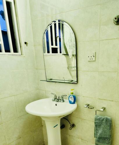 Private Rooms In Osu في آكرا: حمام مع حوض أبيض ومرآة