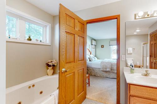een badkamer met een bad, een wastafel en een bed bij Yellow Birch Memories in Eagle River