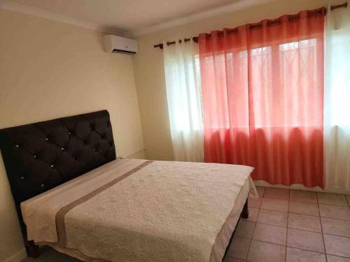 a bedroom with a bed and a red curtain at Browne’s Oceanview Apartments in Arnos Vale