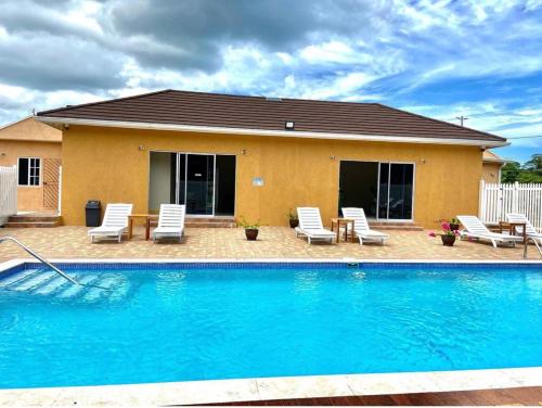 a swimming pool with chairs and a house at Emerald inn at runaway bay in Runaway Bay