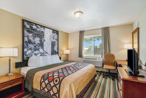 a hotel room with a bed and a desk and a television at Super 8 by Wyndham Mt. Pleasant in Mount Pleasant