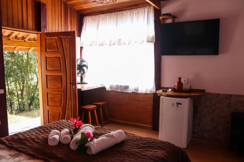 1 dormitorio con 1 cama con toallas y TV en Pousada Estalagem Mirante, en Aiuruoca