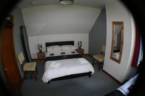 a bedroom with a bed and two chairs and a mirror at The Whitehouse in Dingwall