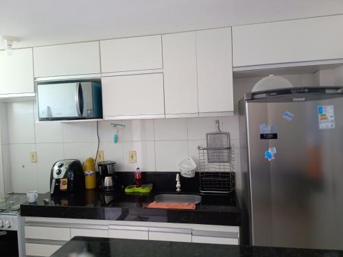 a kitchen with white cabinets and a black counter top at apartamento em Jacumã in Jacumã