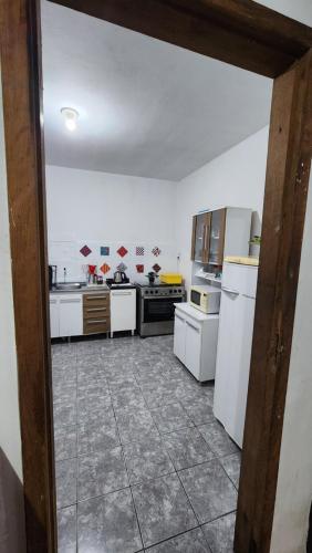 a kitchen with white appliances and a tile floor at Hostel Lumaria 2 in Blumenau