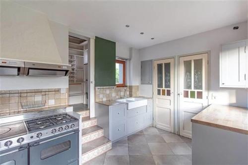 a large kitchen with white cabinets and a stove at Charmante villa des années 30 in Abeiche
