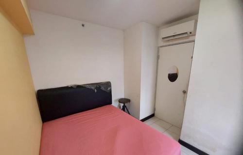 a small bedroom with a red bed and a closet at Apartemen green bay pluit in Jakarta