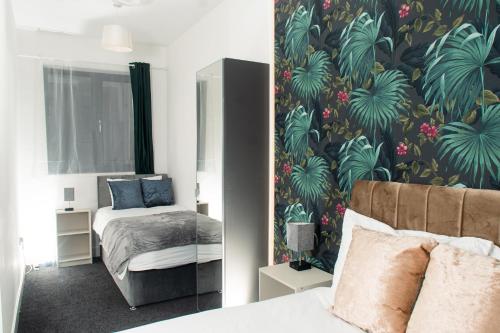 um quarto com uma cama e um papel de parede tropical em Charming and Bright 2 Bedroom Apartment, Close to Stadiums, Transport links, Free Parking em Manchester