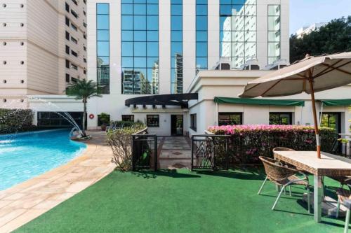 une terrasse avec une piscine, une table et un parasol dans l'établissement Flat Higienópolis Premium, à São Paulo