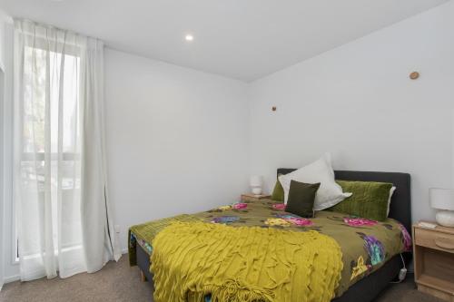 a bedroom with a bed with a yellow blanket at Modern Stylish New 3 Mins CBD in Christchurch