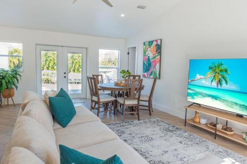 a living room with a couch and a tv at Stunning! Barefoot Breeze - Sale! New Waterfront Listing! Brand New Pool with Putting Green! in Bonita Springs