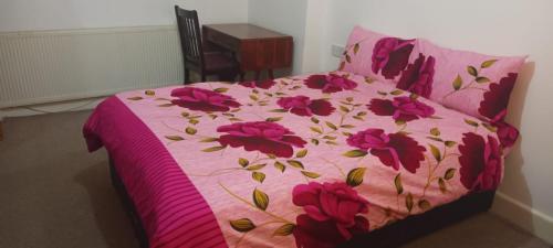a bed with a pink comforter with flowers on it at Greenwich Homestay in London