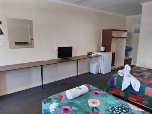 a room with a desk with a television and a bed at Austral Inn in Quorn