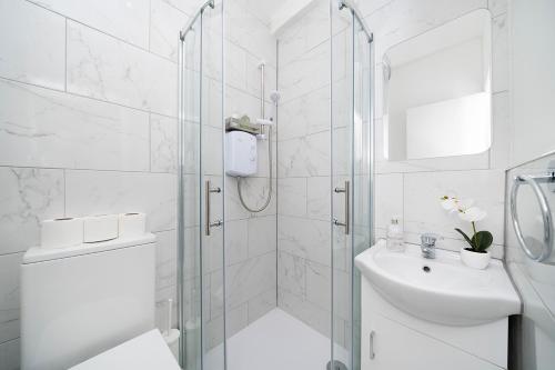 a white bathroom with a shower and a sink at Soho Apartments F2 in London