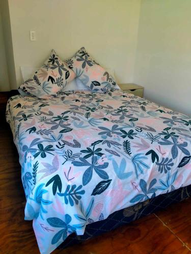 a bed in a bedroom with a floral bedspread at Kaina Kaute in Alofi